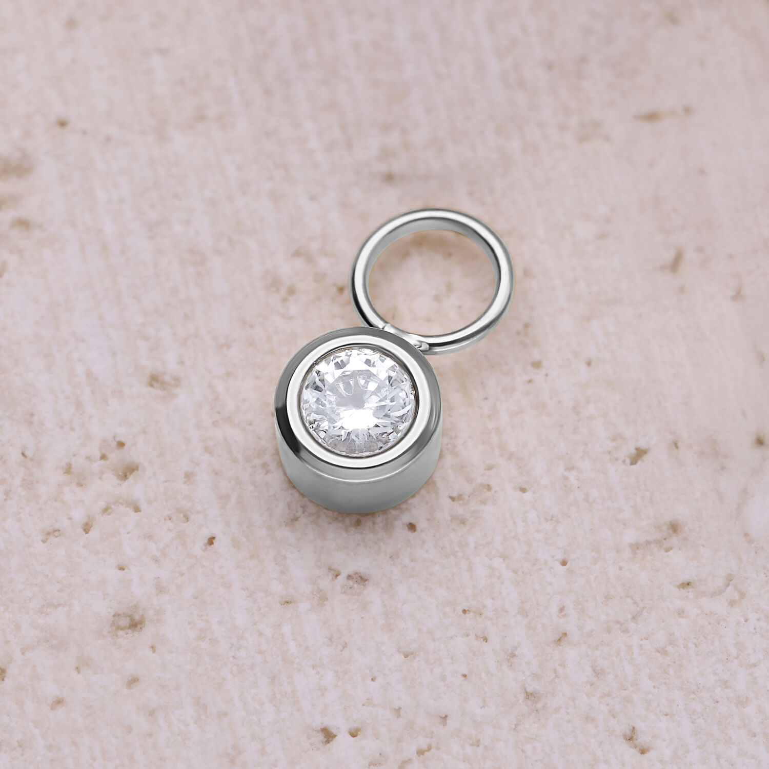 Pendentif rond en cristal en acier chirurgical Pendentif rond en cristal argenté en acier chirurgical sur fond beige