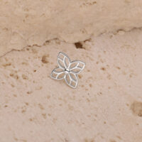 Embout de fleur en argent pour piercings Embout de fleur en argent sur une surface beige texturée