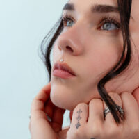 Embout Fleur Push Fit en Argent Gros plan d'un visage avec un piercing fleur en argent sur le nez, fond bleu clair