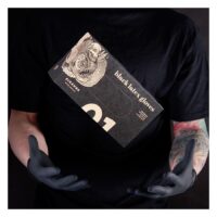 Personne en t-shirt noir tenant une boîte de gants en latex Piranha noirs devant un fond sombre