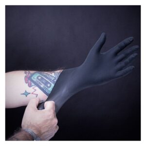 Gant en latex noir enfilé sur un bras tatoué
