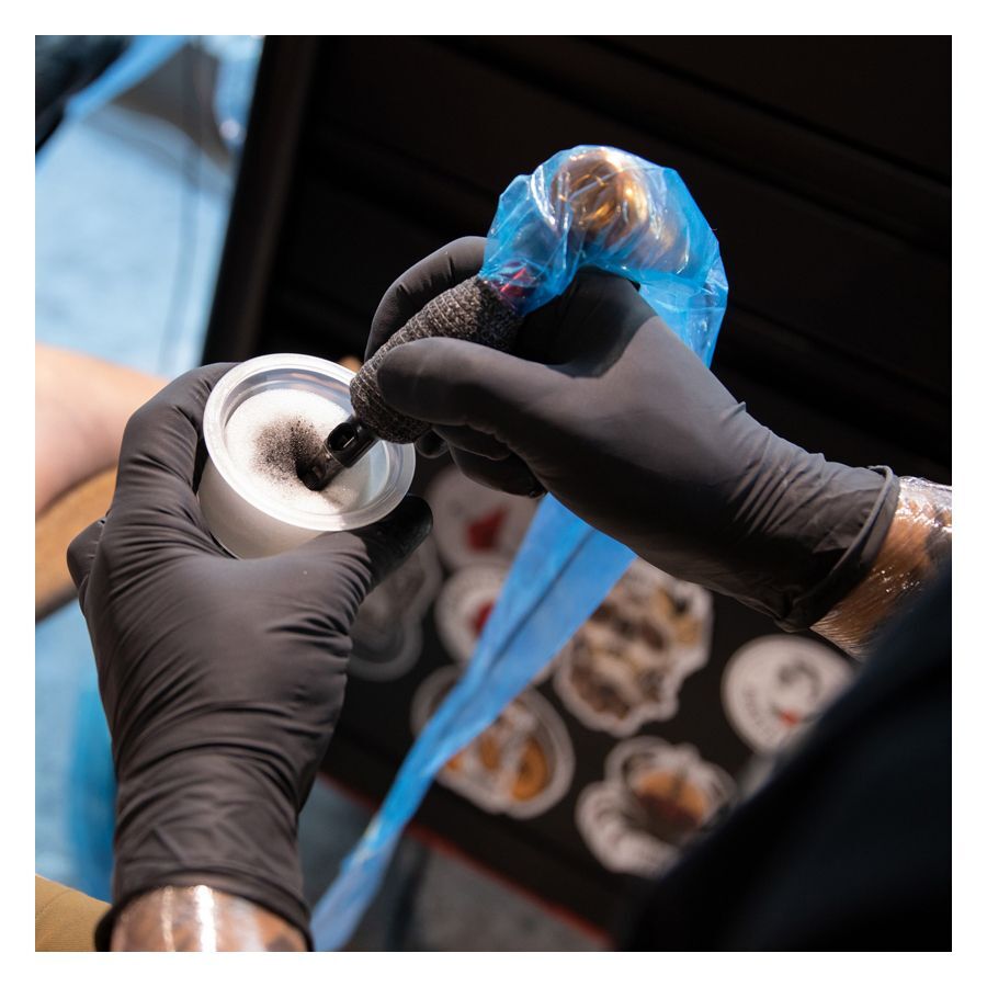Gants en latex noirs de Wildcat lors d'un tatouage avec couverture bleue