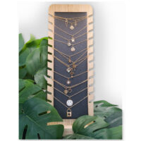 Présentoir à bijoux noir en simili cuir et bois Présentoir noir en simili cuir et bois avec des colliers et des plantes en arrière-plan
