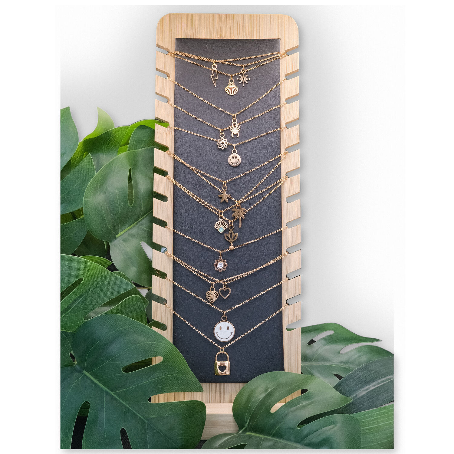 Présentoir à bijoux noir en simili cuir et bois Présentoir noir en simili cuir et bois avec des colliers et des plantes en arrière-plan