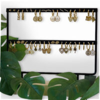 Présentoir noir pour boucles d'oreilles avec plantes Présentoir noir pour boucles d'oreilles dorées, entouré de feuilles vertes
