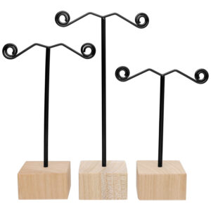 Trois présentoirs à boucles d'oreilles noirs avec base en bois naturel sur fond blanc