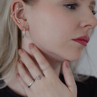 Élégant anneau torsadé en argent porté Femme avec plusieurs boucles d'oreilles portant un anneau torsadé en argent