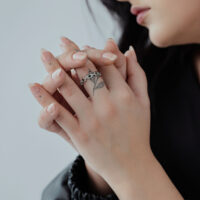 Bague en maillons d'argent portée à la main Bague en maillons d'argent sur les mains d'une personne avec des doigts tatoués et des manches noires