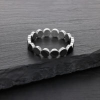 Bague plate en argent en acier chirurgical Bague en argent en acier chirurgical sur une surface en pierre sombre