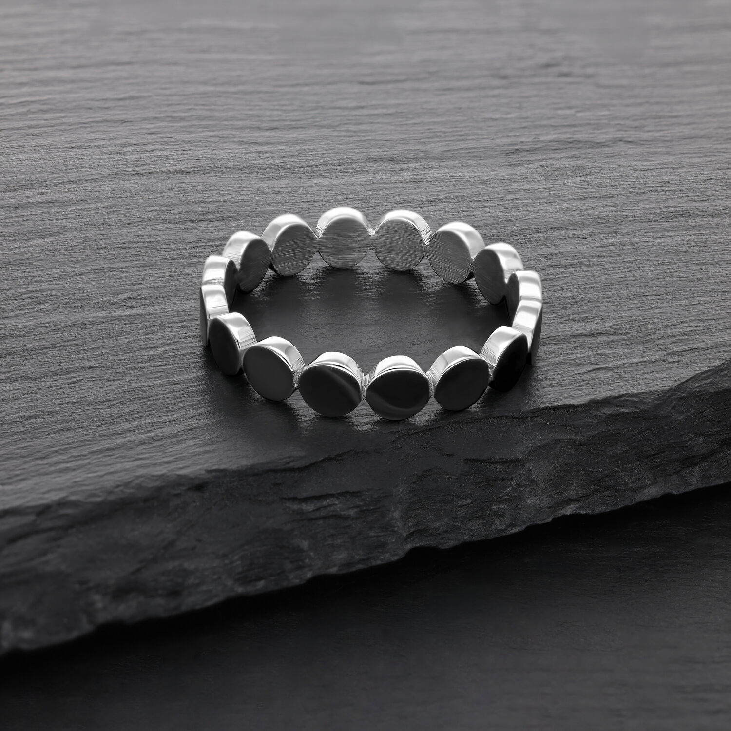 Bague plate en argent en acier chirurgical Bague en argent en acier chirurgical sur une surface en pierre sombre