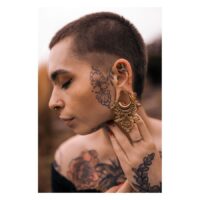 Selles d'oreilles baroques style vintage Selles d'oreilles en style baroque en acier doré, portées par une personne tatouée en extérieur
