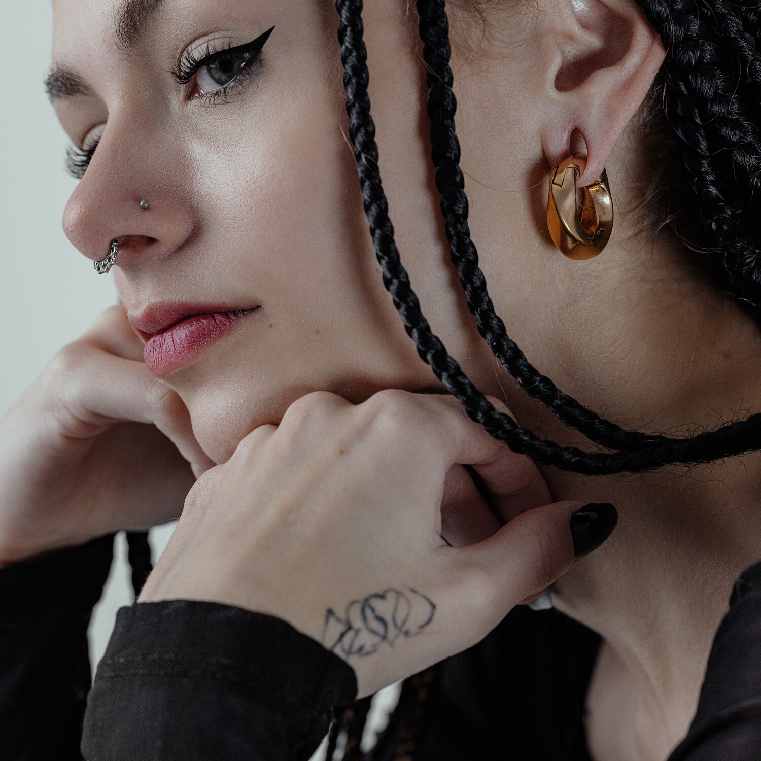 Twisted poids d'oreille en or portés à l'oreille Femme avec des poids d'oreille Twisted en or et des tresses sur fond gris