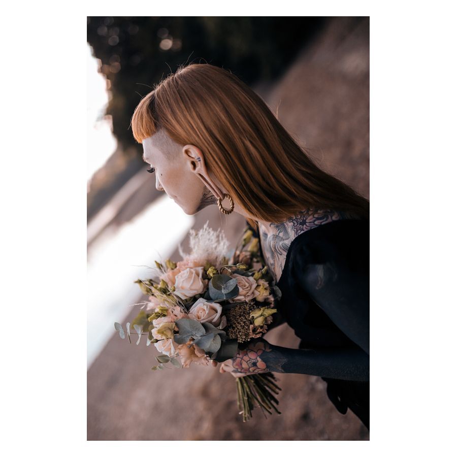 Poids d'oreille tressés en acier chirurgical Personne avec des poids d'oreille tressés et un bouquet de fleurs au bord du lac