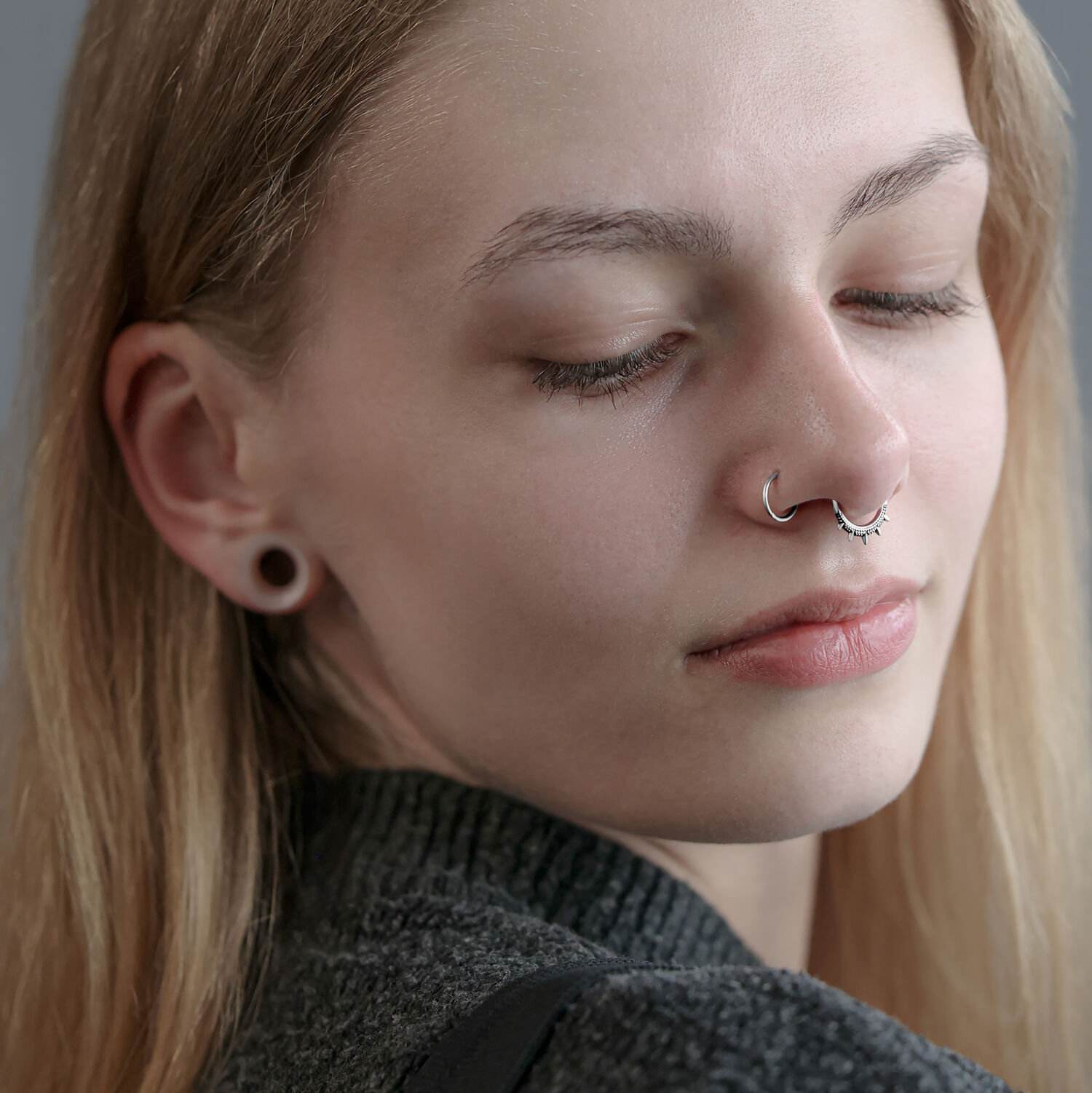 Clicker Oriental à Pointes en Argent pour le Septum Femme avec un clicker septum en argent et des lobes d'oreilles étirés sur fond gris