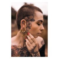 Personne avec des piercings Labret Mandala dorés et des tatouages sur le visage et le corps