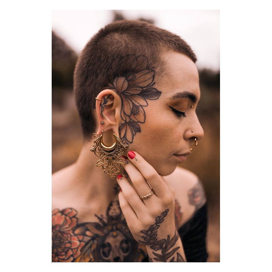 Personne avec des piercings Labret Mandala dorés et des tatouages sur le visage et le corps