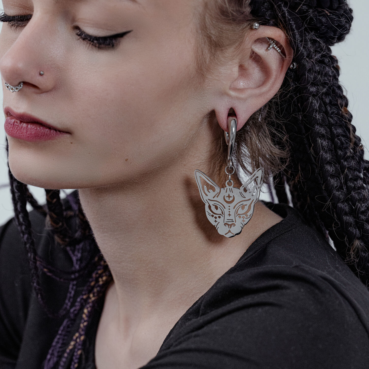 Poids d'oreille Sphynx en acier chirurgical Femme aux cheveux tressés portant un poids d'oreille Sphynx en argent.