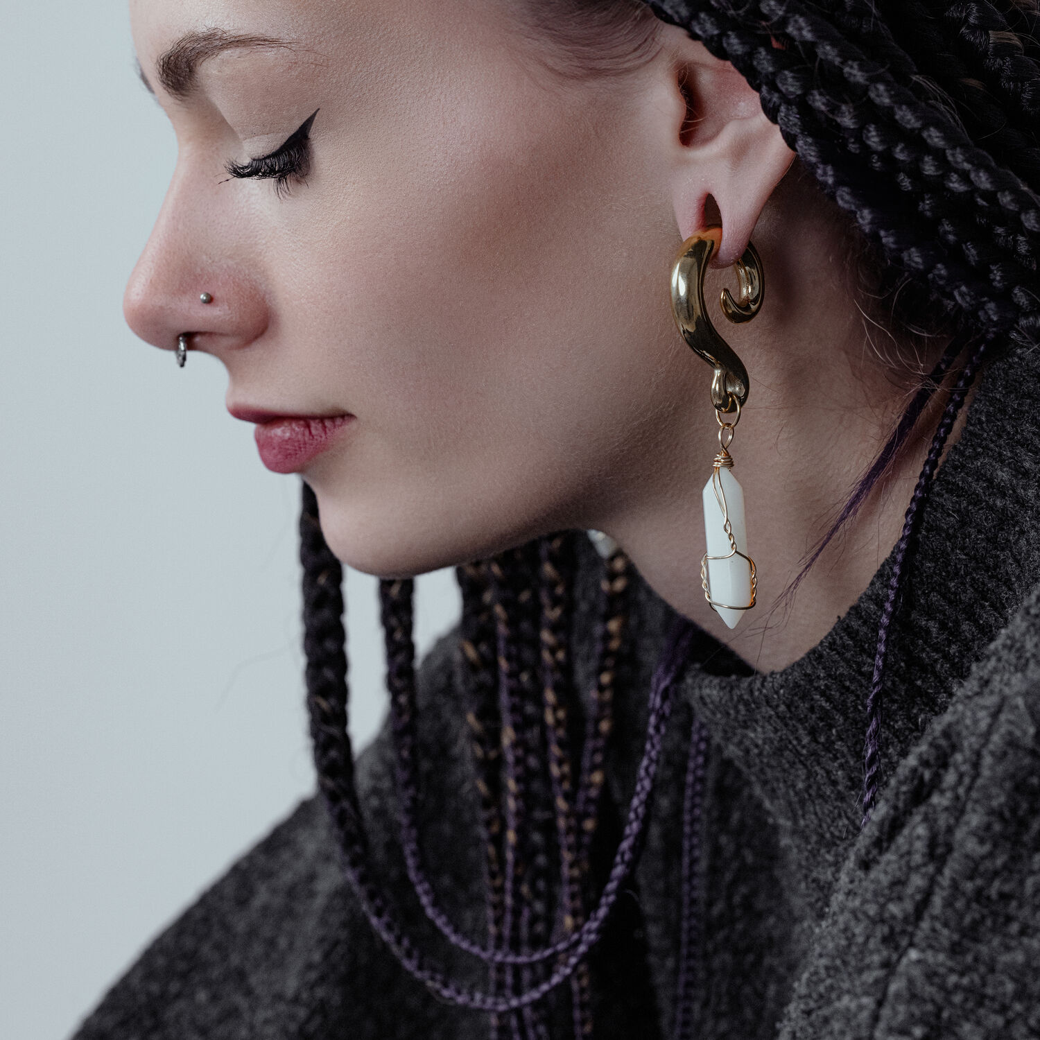 Poids d'oreilles en pierre Opilate dorés à l'oreille Femme aux cheveux tressés portant des poids d'oreilles dorés avec des pierres blanches.