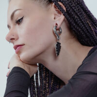 Femme avec poids d'oreille pendants en obsidienne argentée, profil latéral