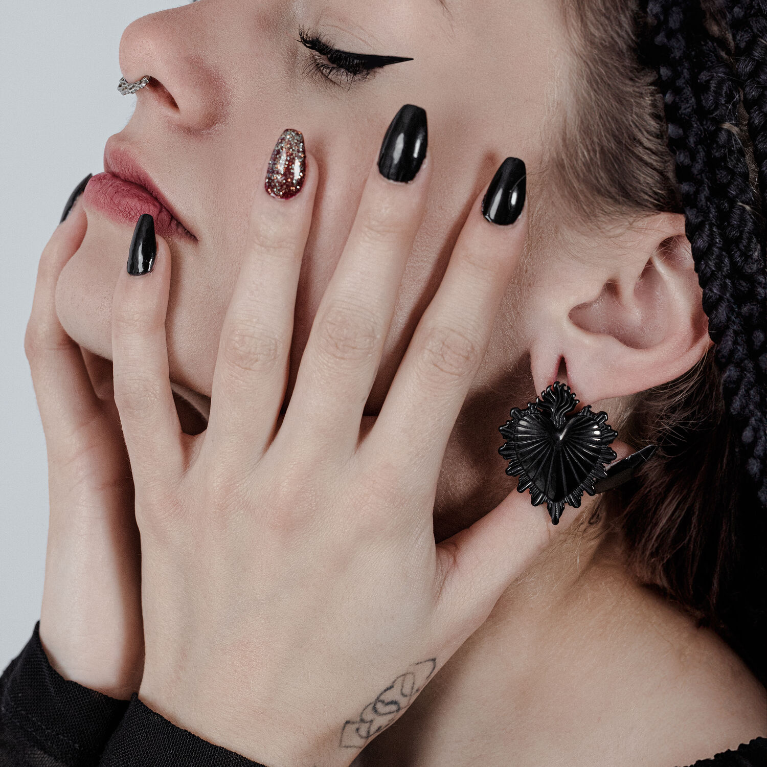 Poids d'oreille Sacred Heart noirs dans l'oreille Femme avec des poids d'oreille Sacred Heart noirs et vernis à ongles noir, vue de côté