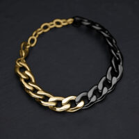 Bracelet avec maillons dorés et noirs sur fond sombre