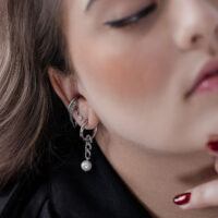 Boucles d'oreilles en argent avec pendentif perle Gros plan sur des créoles en argent avec pendentif perle à l'oreille d'une personne