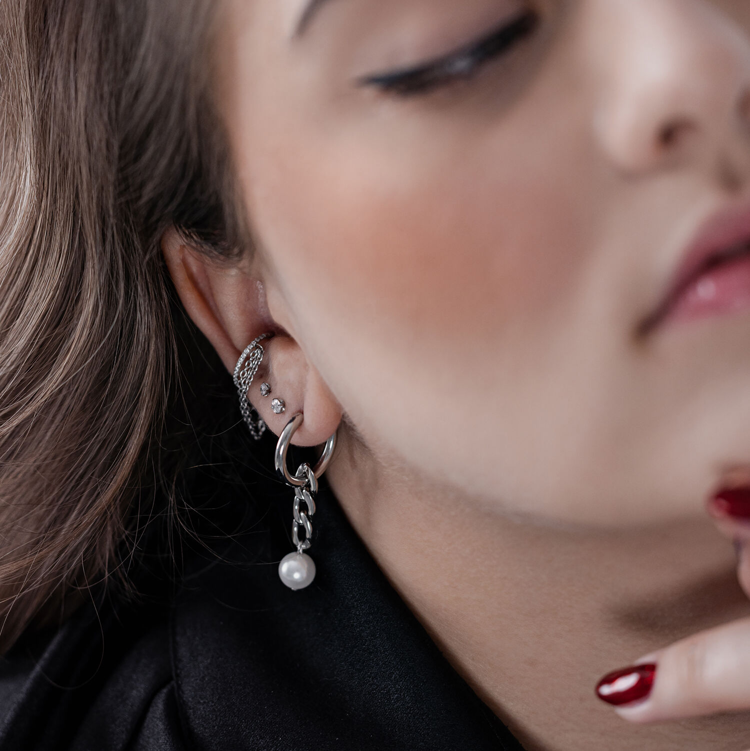 Boucles d'oreilles en argent avec pendentif perle Gros plan sur des créoles en argent avec pendentif perle à l'oreille d'une personne