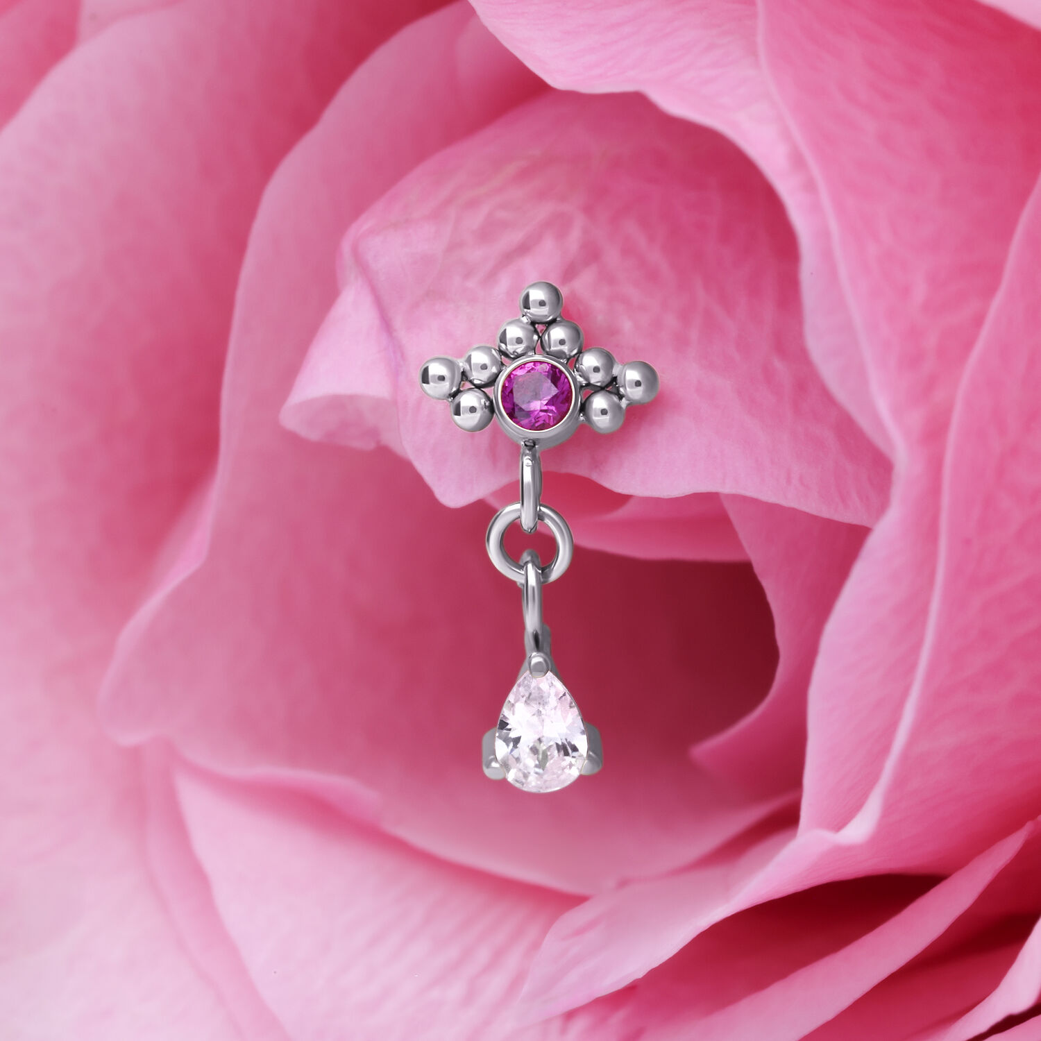 Pendentif de piercing argenté avec cristal rouge Pendentif de piercing argenté avec cristal rouge et forme de goutte devant un pétale rose