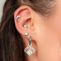 Gros plan d'une oreille avec plusieurs piercings, dont un piercing en opale avec chaîne