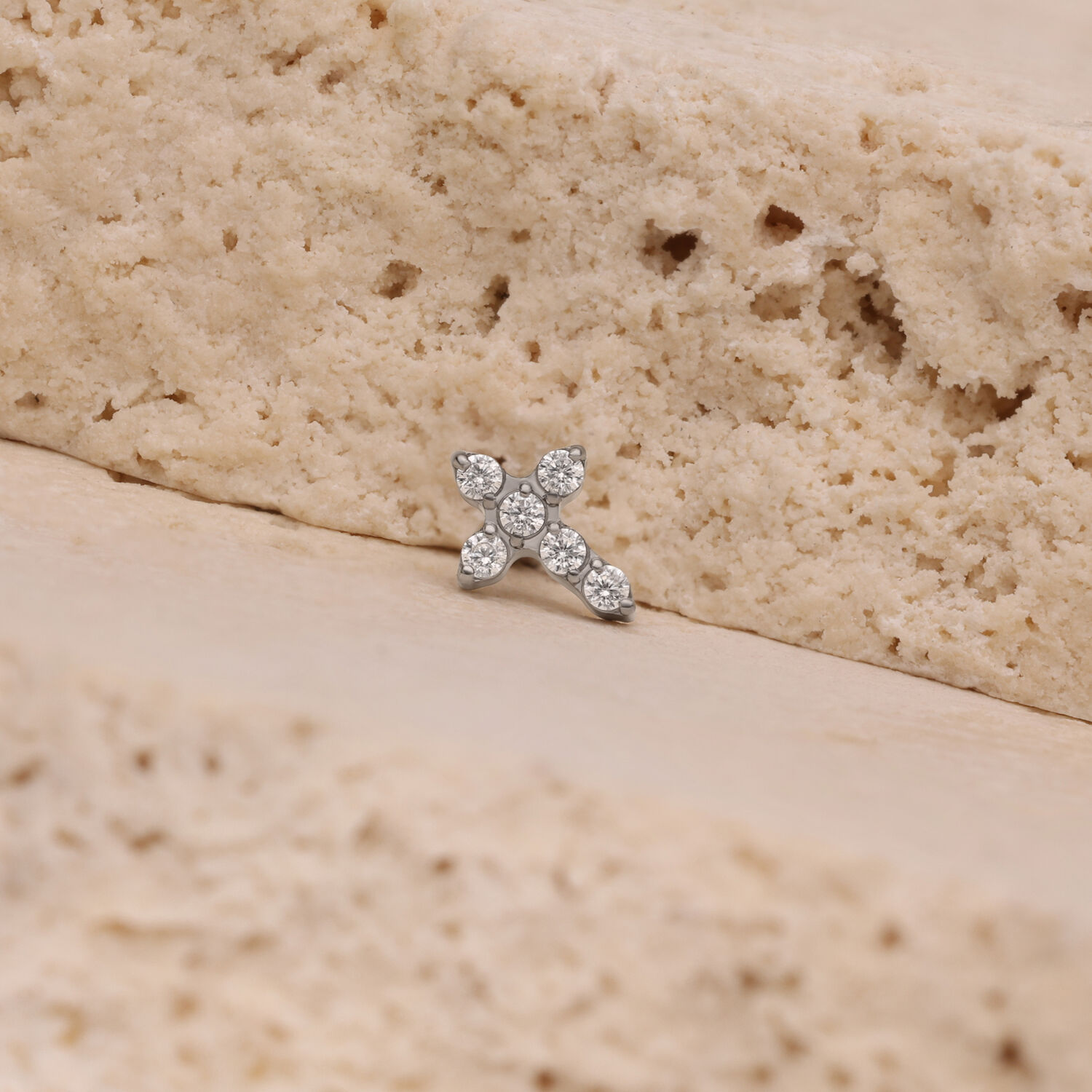Petit embout croix en cristal, argent Petit embout croix en cristal argenté sur surface en pierre beige