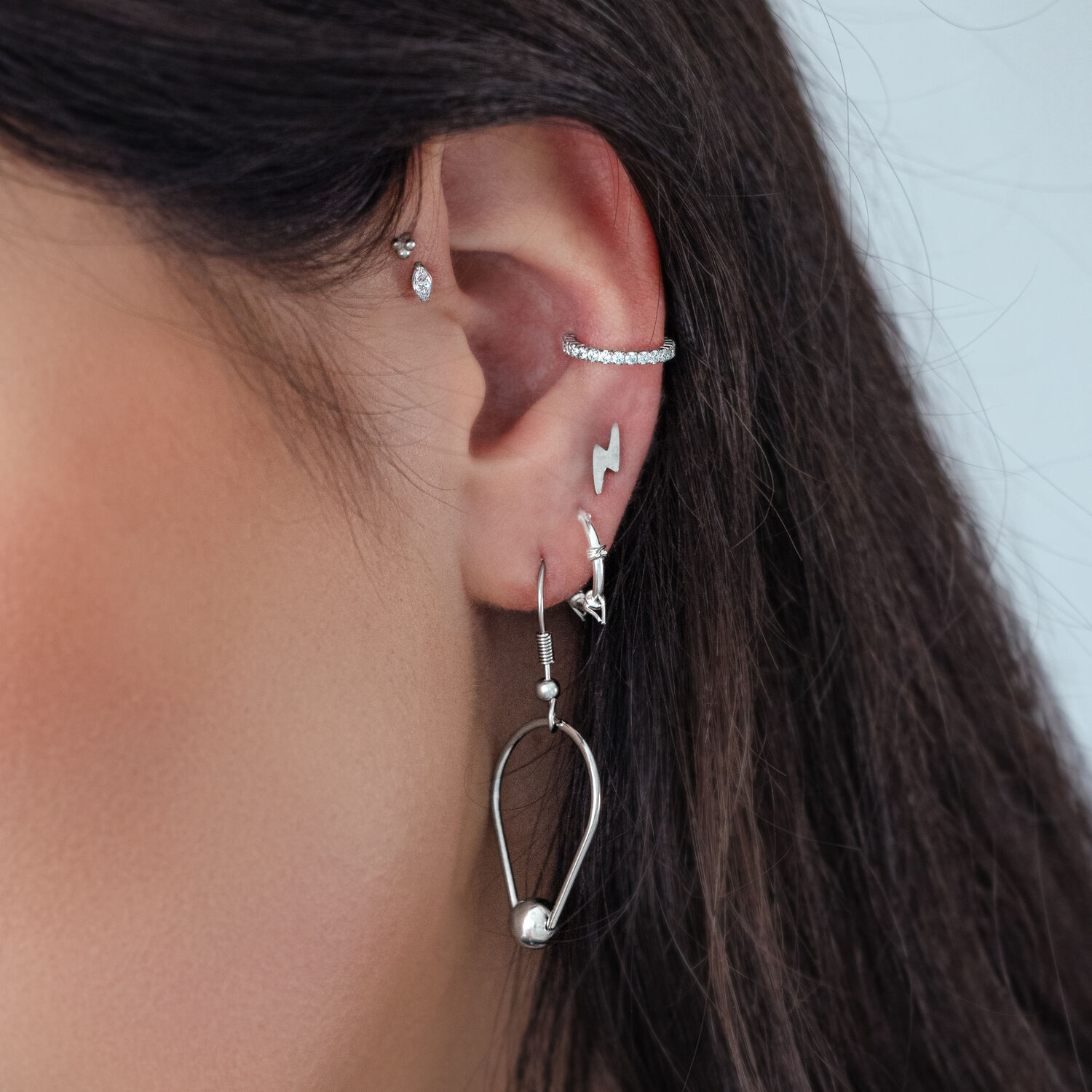 Piercings d'oreille en argent avec cristaux Gros plan d'une oreille avec plusieurs piercings en argent, y compris un embout en cristal