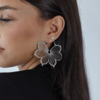 Femme avec un grand embout papillon argenté dans l'oreille, fond noir