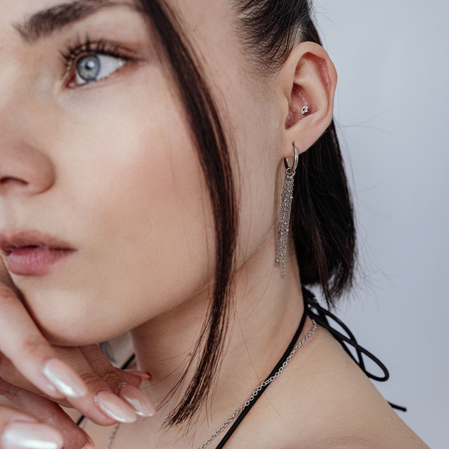 Femme avec embout floral Push Fit dans l'oreille, collier et boucles d'oreilles en argent, fond blanc