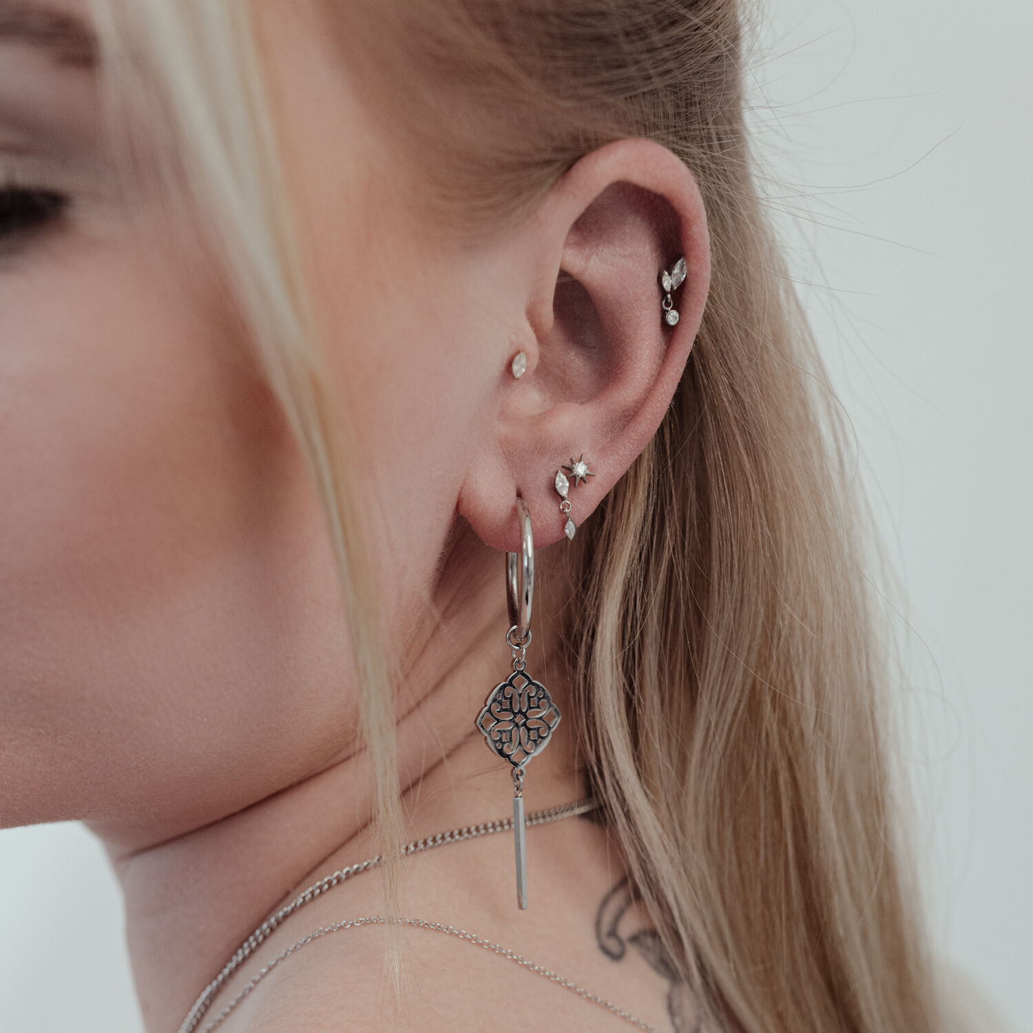 Embout Étoile en Cristal Push Fit à l'Oreille Gros plan d'une oreille avec plusieurs piercings, dont un grand embout étoile en cristal argenté Push Fit.