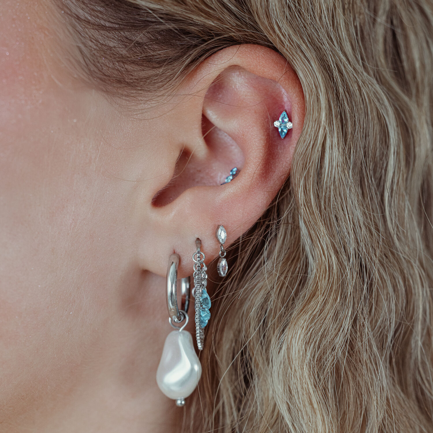 Embout Push Fit Argenté avec Cristal Turquoise Oreille avec plusieurs piercings, y compris un embout Push Fit argenté avec cristal turquoise
