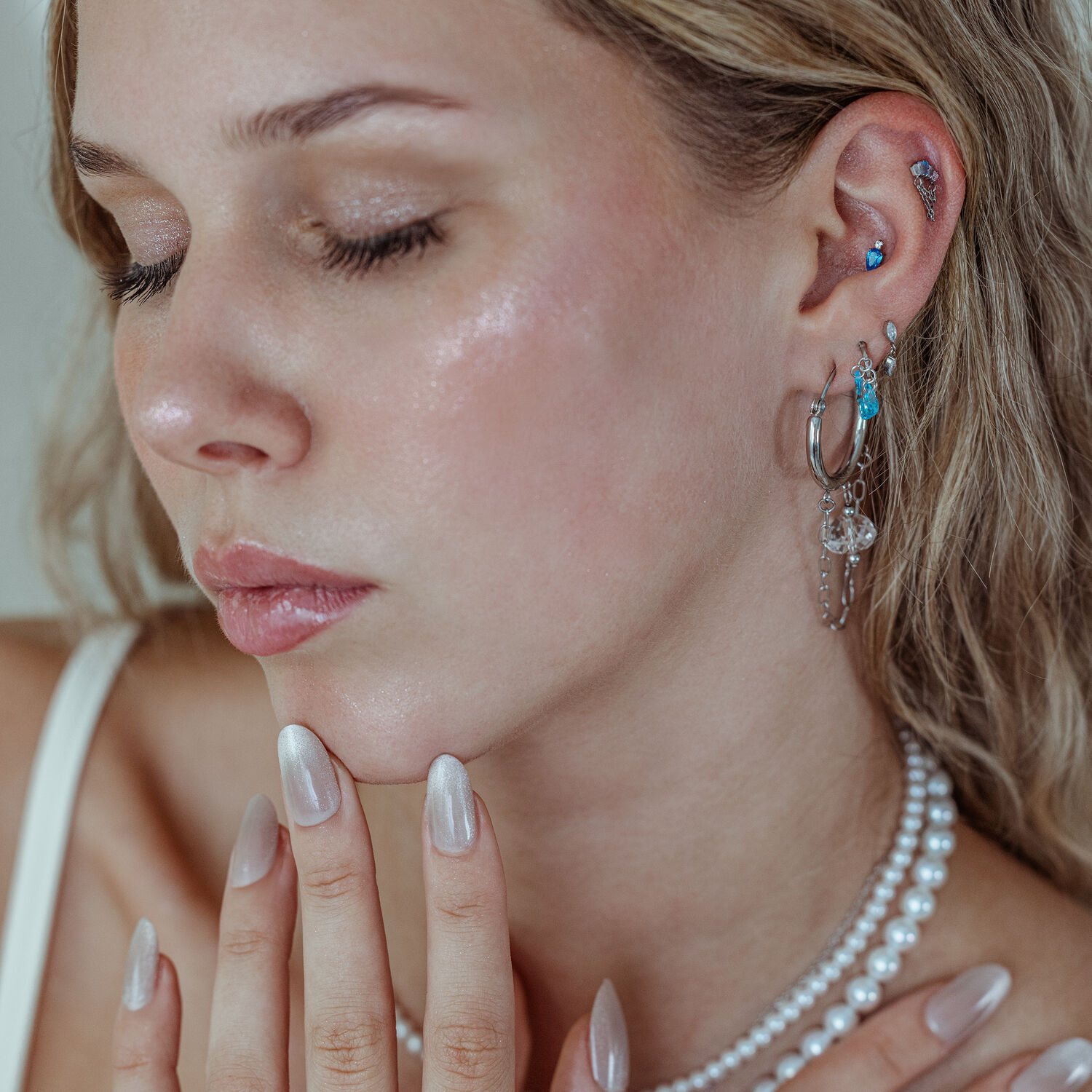 Mystic Dew embout argent et or pour l'oreille Femme avec plusieurs piercings d'oreille, y compris l'embout Mystic Dew en argent et or avec des cristaux lavande et turquoise, sur fond neutre