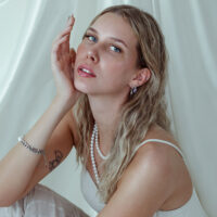 Femme avec embout cristal Push Fit en lavande à l'oreille sur fond blanc