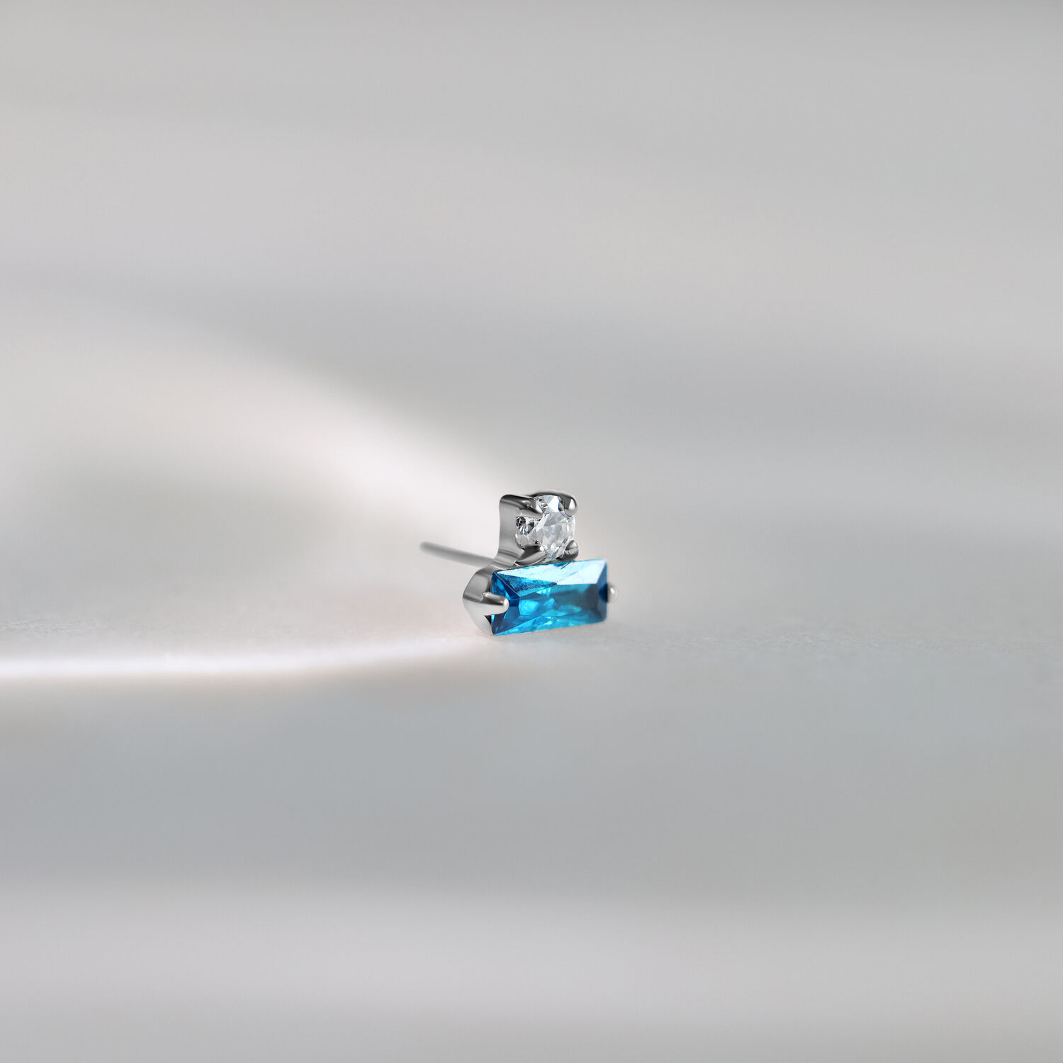 Embout Push Fit Argenté avec Cristal Turquoise Embout de piercing argenté avec cristal turquoise rectangulaire sur fond gris