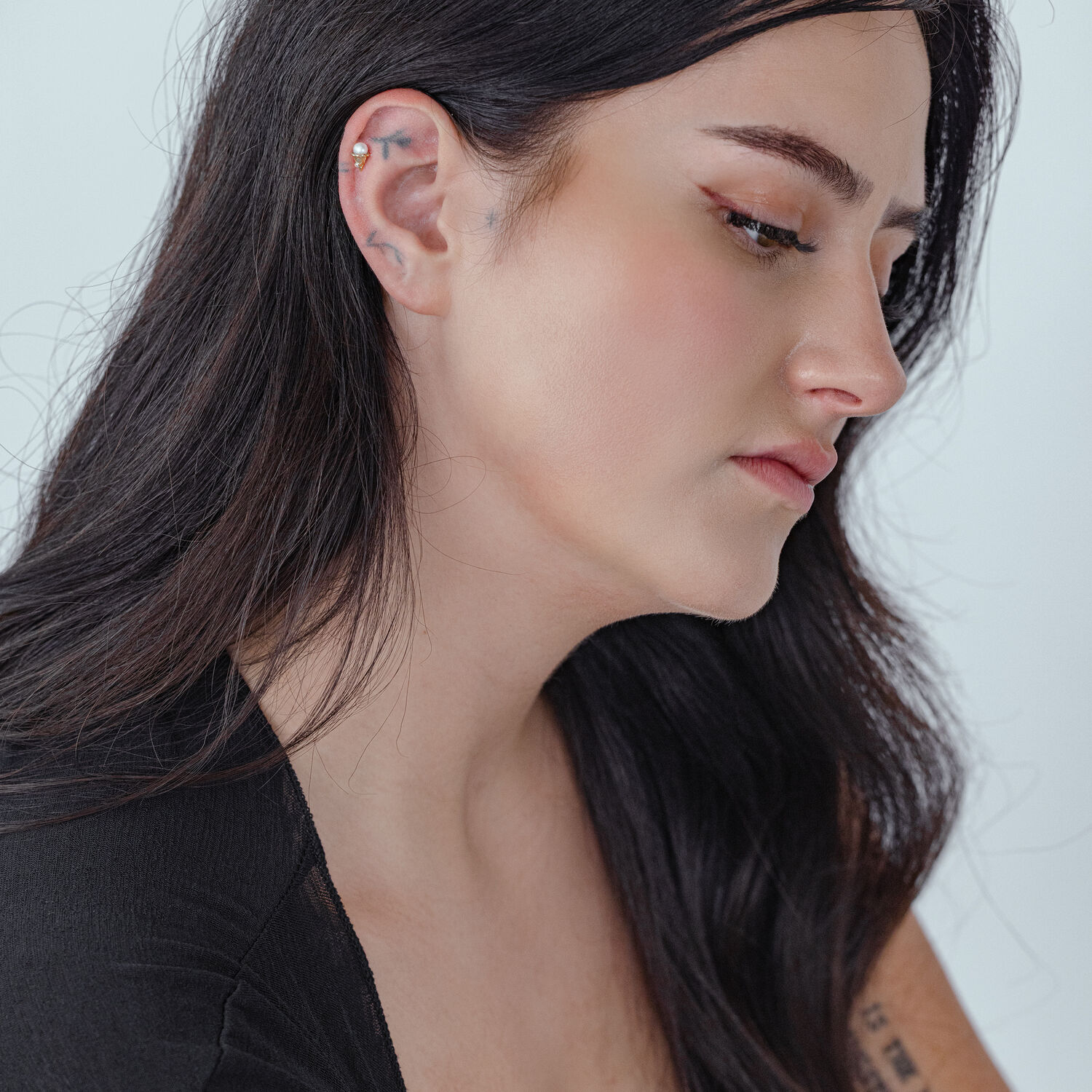 Embout Push Fit en titane doré dans l'oreille Femme avec un embout Push Fit en titane doré dans l'oreille, vue de côté sur fond blanc