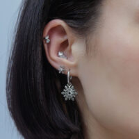 Embout de piercing flocon de neige argenté Oreille avec plusieurs piercings argentés, design flocon de neige, sur fond neutre