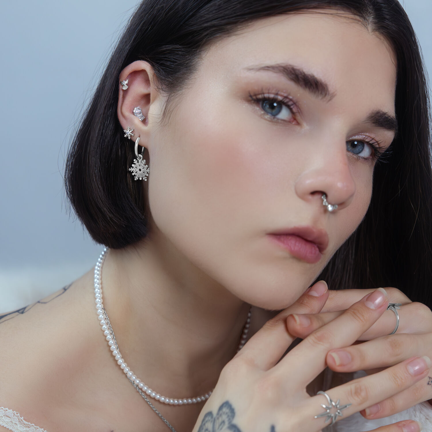 Femme avec plusieurs piercings, dont un embout argenté Snow Angel à l'oreille, sur fond neutre.