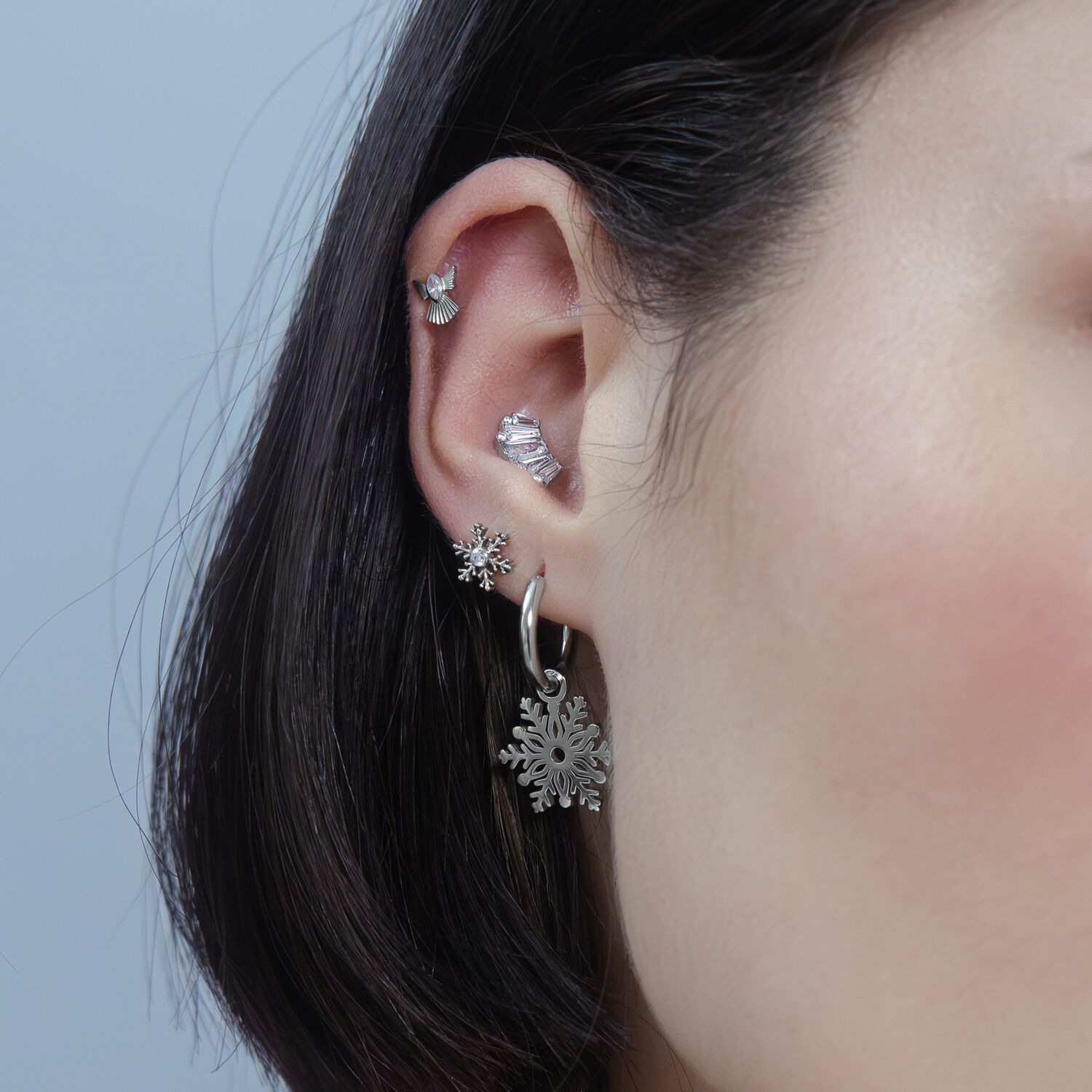 Femme avec un piercing Snow Angel argenté à l'oreille, fond neutre