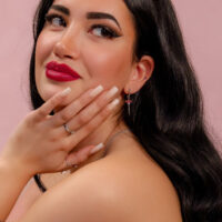 Embout Push Fit argenté avec cristal rouge Femme aux longs cheveux noirs, lèvres rouges et boucle d'oreille argentée avec cristal rouge sur fond rose