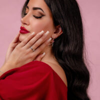 Push Fit embout ornemental rubis argenté Femme aux lèvres rouges et cheveux longs et lisses portant un embout d'oreille argenté sur fond rose