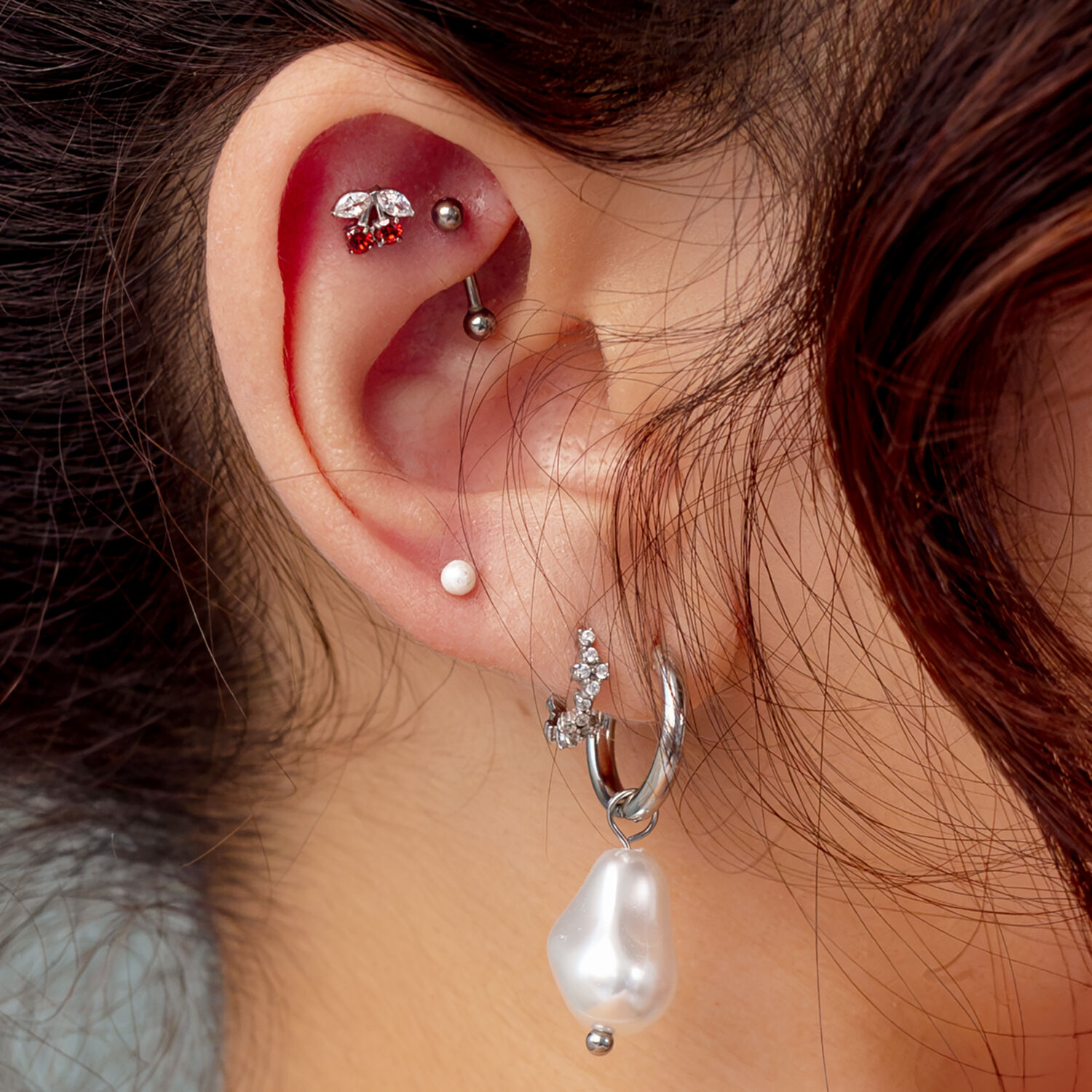 Embout Cerises Argenté Push Fit Oreille avec plusieurs piercings, y compris un embout cerises argenté avec pierre rouge