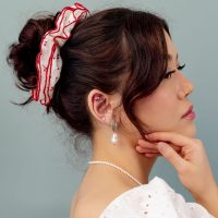 Accessoire pour cheveux avec ruban rouge Femme avec cheveux relevés, bandeau rouge et boucles d'oreilles en perles sur fond gris