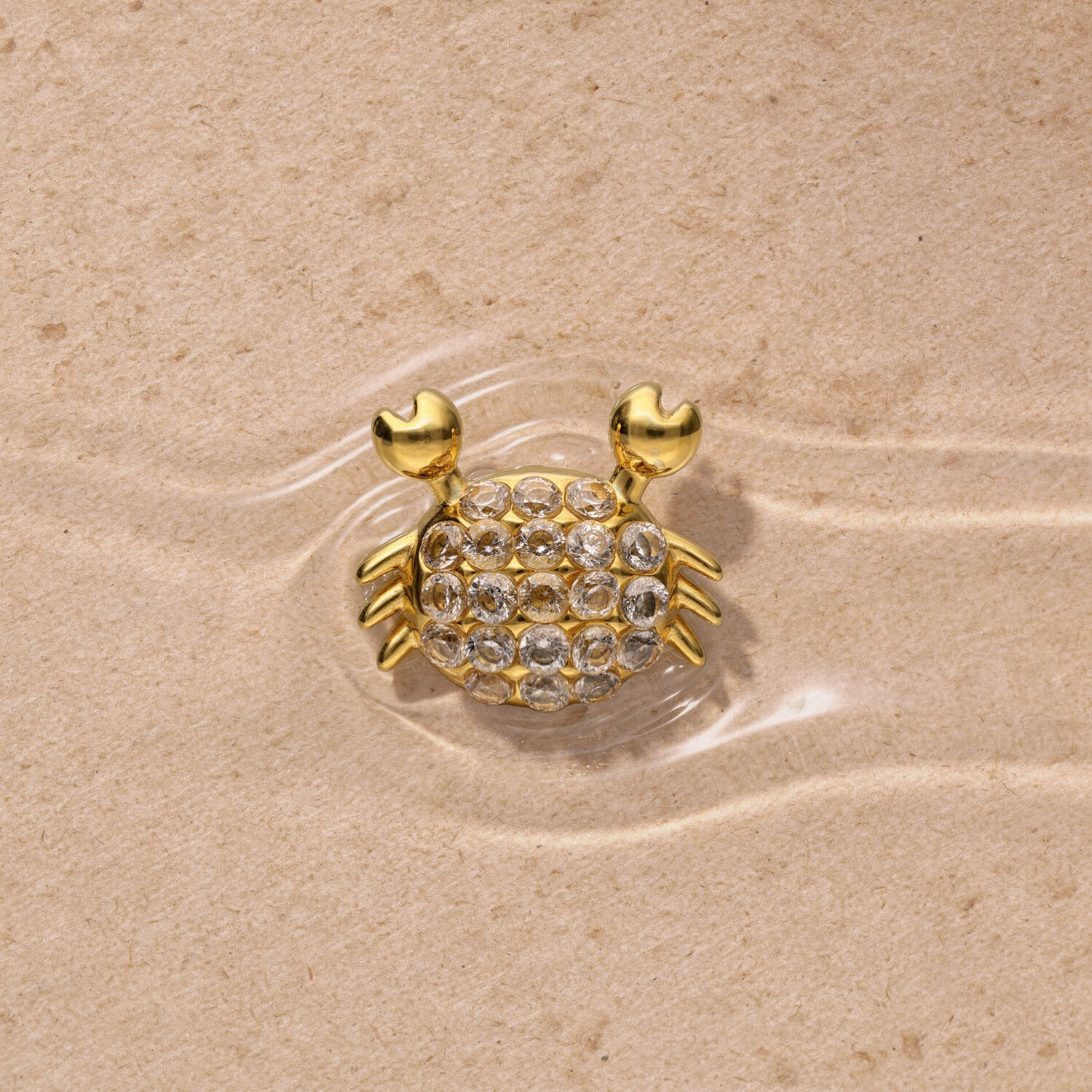 Embout Crabe Push Fit Doré Embout crabe doré avec strass sur fond sableux