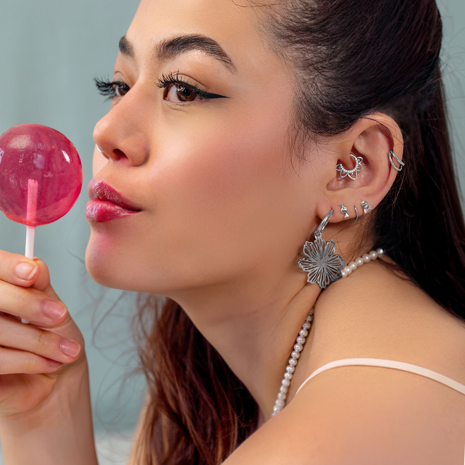 Piercings d'oreille argentés avec Lollipop Femme avec plusieurs piercings d'oreille argentés et un Lollipop rose, de côté