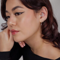Piercing d'oreille argenté avec design de lune Femme avec plusieurs piercings argentés, y compris un design en forme de lune à l'oreille sur fond clair