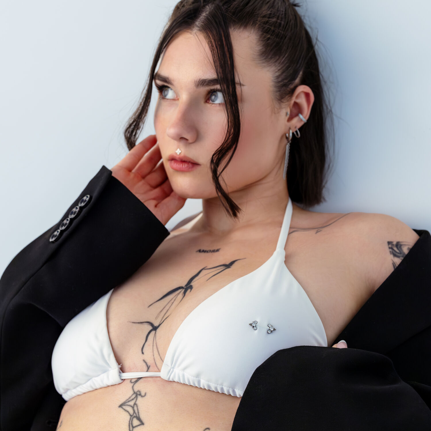Haut de bikini blanc avec blazer noir Femme avec haut de bikini blanc et blazer noir, tatouages visibles, sur fond clair